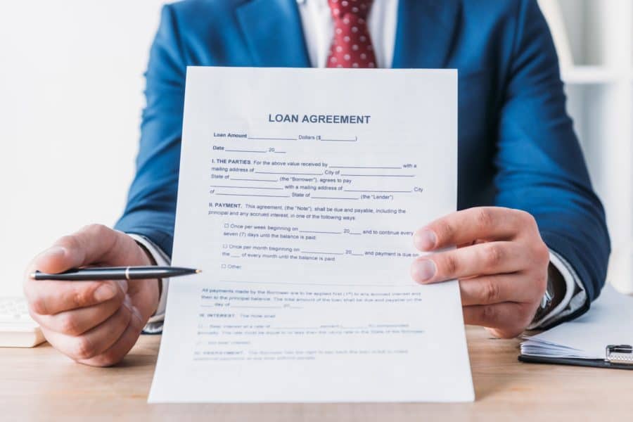 partial view of businessman pointing with pen at loan agreement